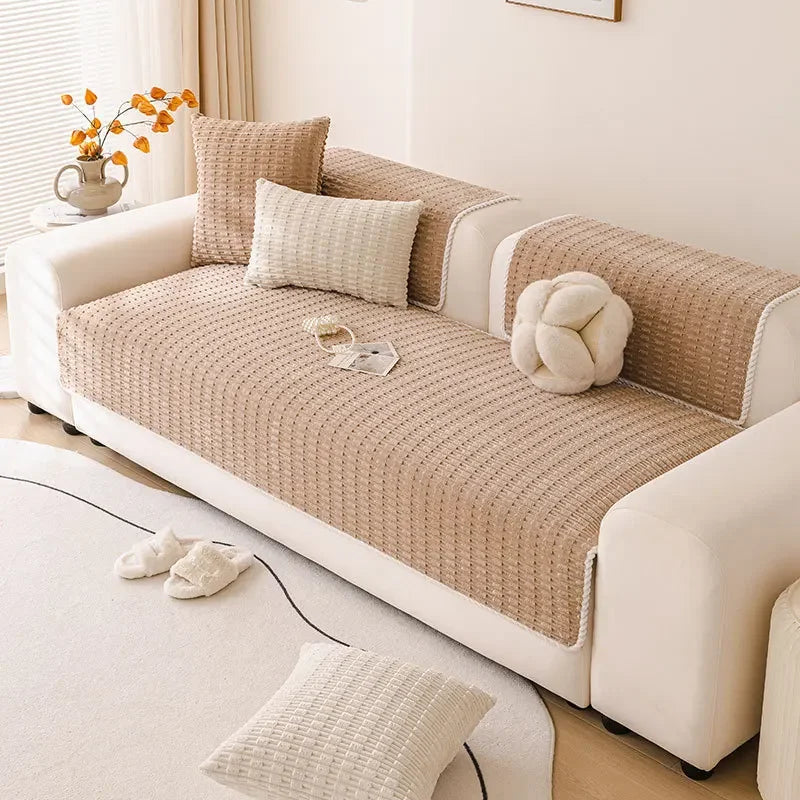 A beige non-slip sofa cover with a quilted texture and light cream cushions on a white sofa.