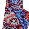 Close-up of a vibrant African wax print fabric featuring intricate floral patterns in purple, orange, and turquoise.