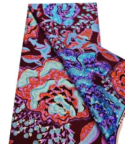 Close-up of a vibrant African wax print fabric featuring intricate floral patterns in purple, orange, and turquoise.