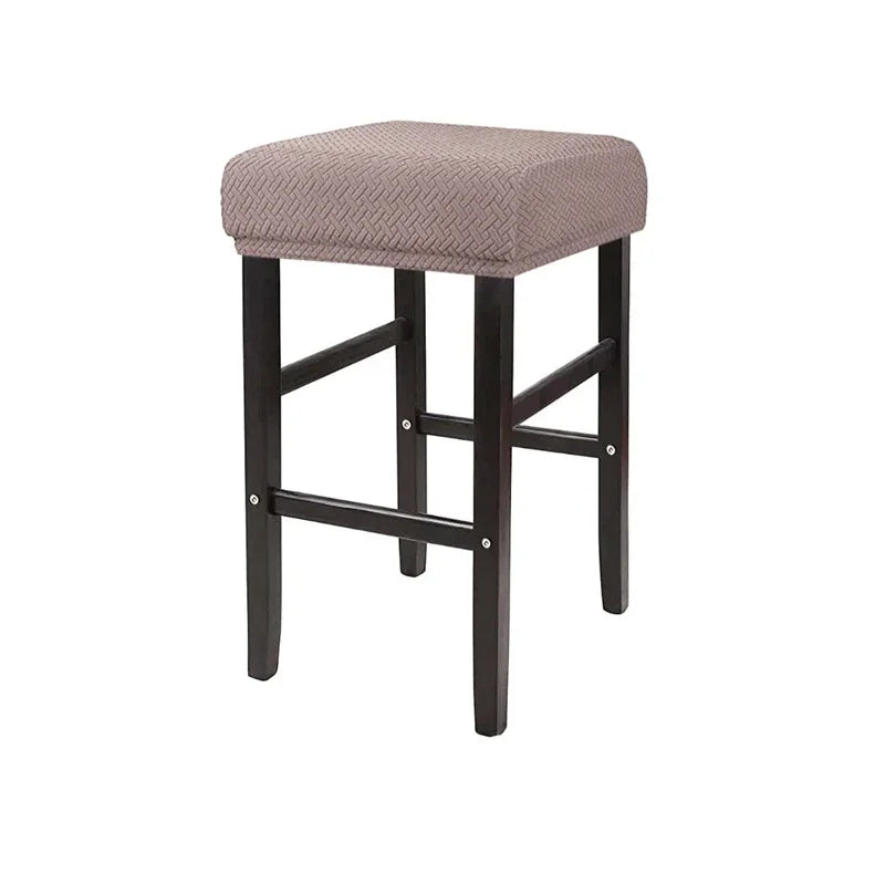 A square bar stool with a beige woven fabric slipcover and dark wood legs.