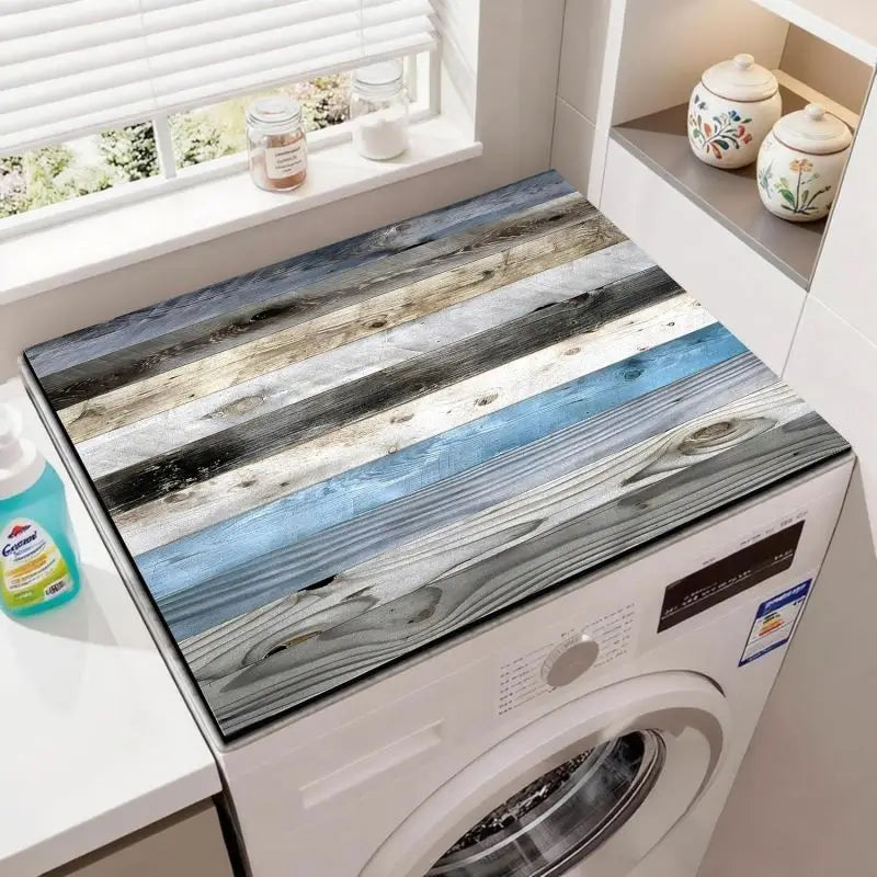 A close-up of a white washing machine with a wood grain fridge cover mat featuring horizontal stripes of blue, gray, and beig