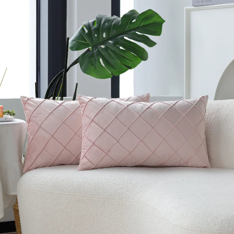 Two pink quilted velvet decorative pillow covers resting on a white sofa.