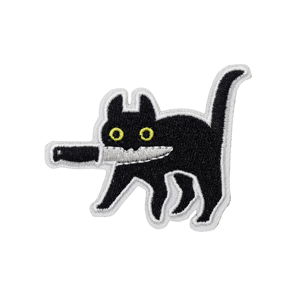 An embroidered tactical patch of a black cat with yellow eyes and a visible tooth, featuring a stylized assassin theme.