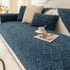A deep teal plush sofa cushion cover with a quilted texture and cream accent pillows.