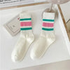 A pair of white crew socks with horizontal pink and teal stripes displayed on a white surface.
