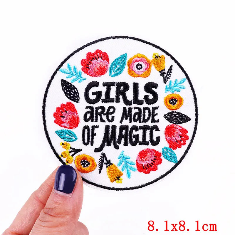 A circular embroidered patch with the text Girls are made of magic in colorful floral embroidery.