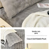 A gray plush long pillowcase with a white knitted blanket and a small photo on a bed.