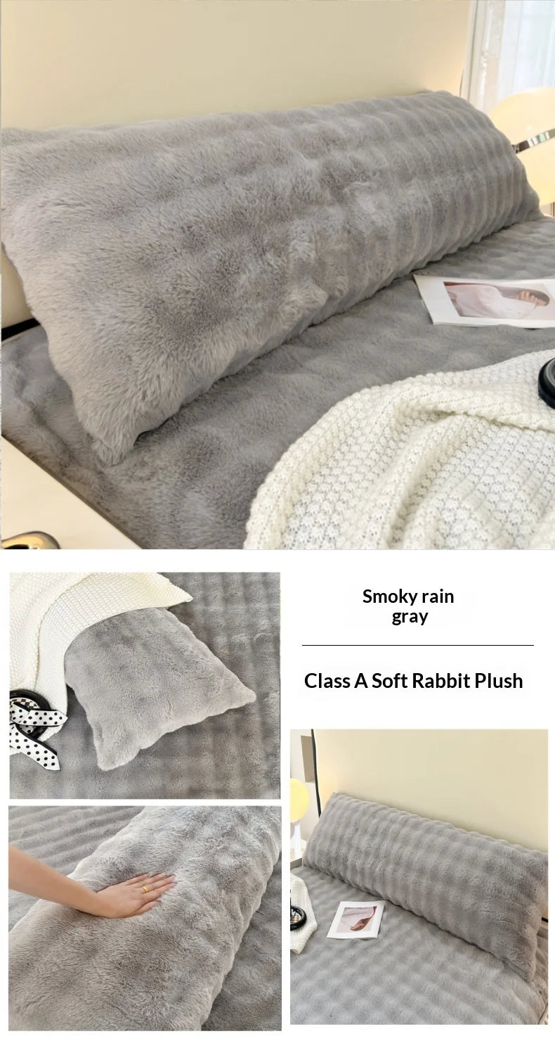 A gray plush long pillowcase with a white knitted blanket and a small photo on a bed.
