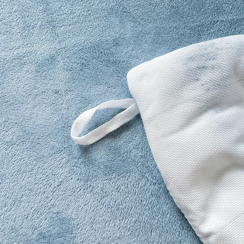 A white cozy rabbit fleece duvet cover with a white drawstring is displayed on a blue textured fabric.