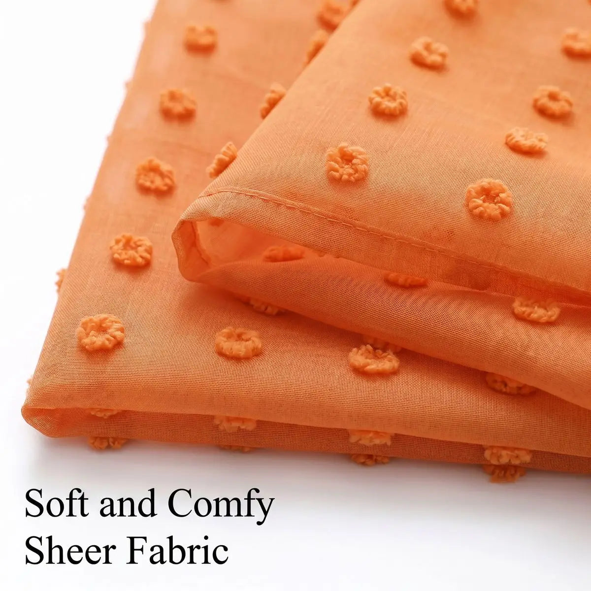 Orange sheer fabric with small pompom detailing shown in a folded textile.
