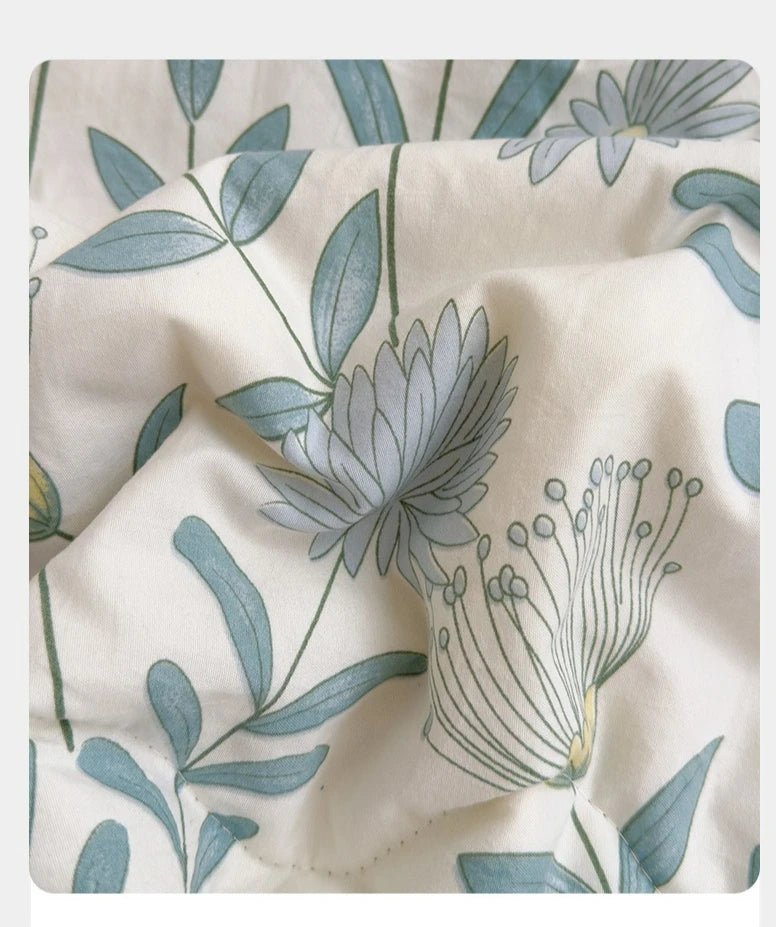 A close-up of a white fabric with a blue botanical print featuring leaves and a large daisy flower.