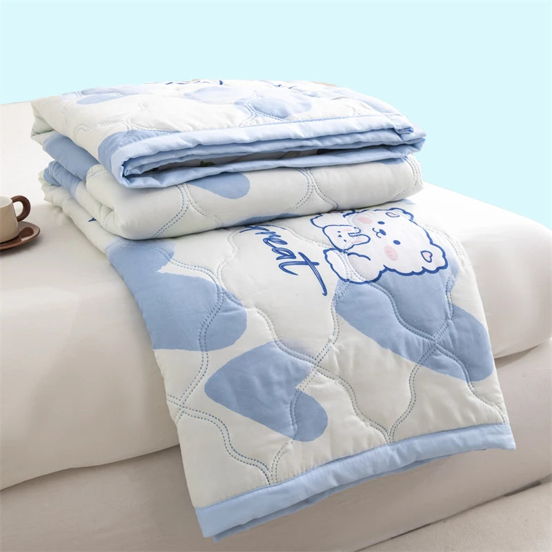 A stack of light blue and white quilted blankets featuring a cute bear design on a white background.