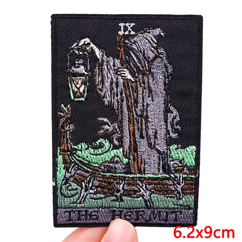 A black embroidery patch featuring the Roman numeral IX above a depiction of a hermit figure and a deer.