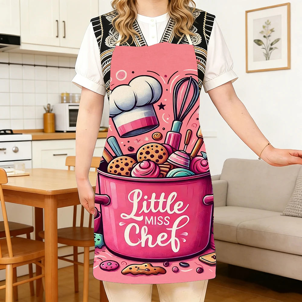 A woman wearing a pink kitchen apron with a baking design and a chef hat illustration.