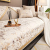 A bed with gold foil patterned bedding, white pillows, and a draped white throw blanket.