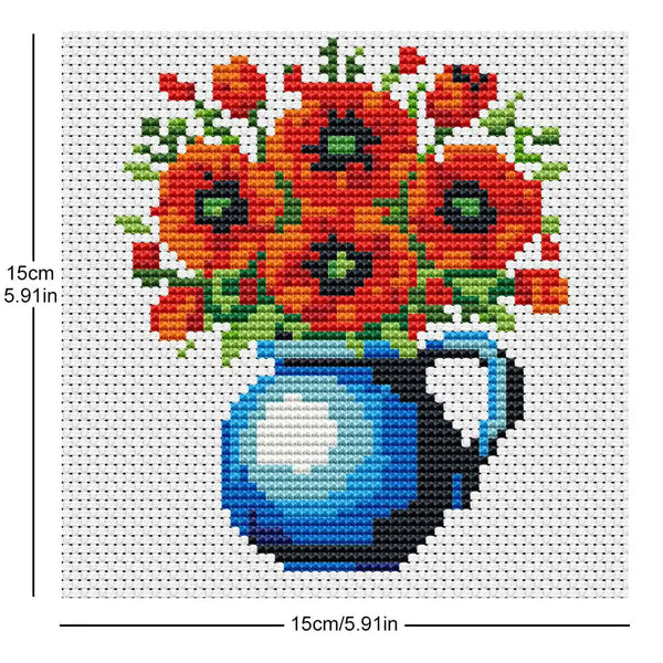 A cross stitch design featuring a bouquet of orange and red flowers in a blue vase.