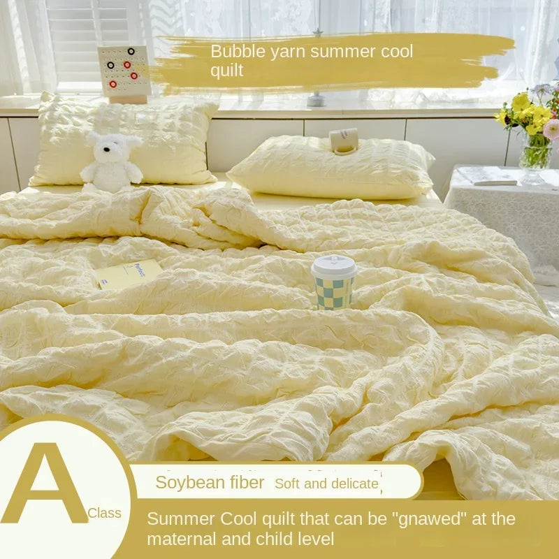 A yellow bubble yarn summer cool quilt displayed on a bed with white pillows and bedding.