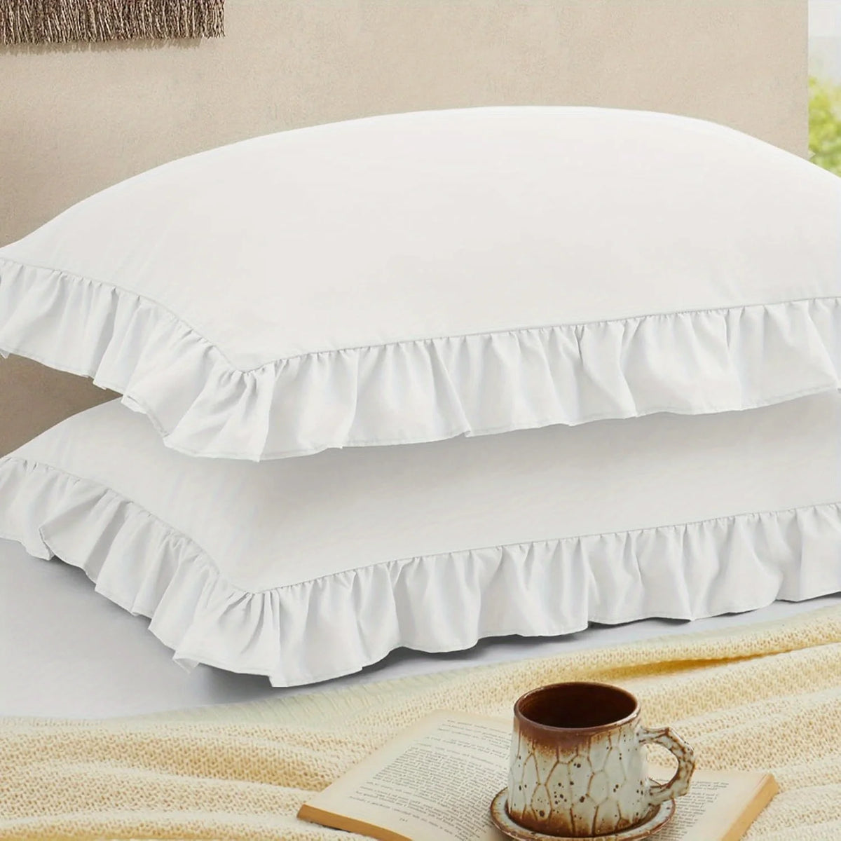 A set of two white pillow covers with ruffled envelope closures stacked on a light surface.