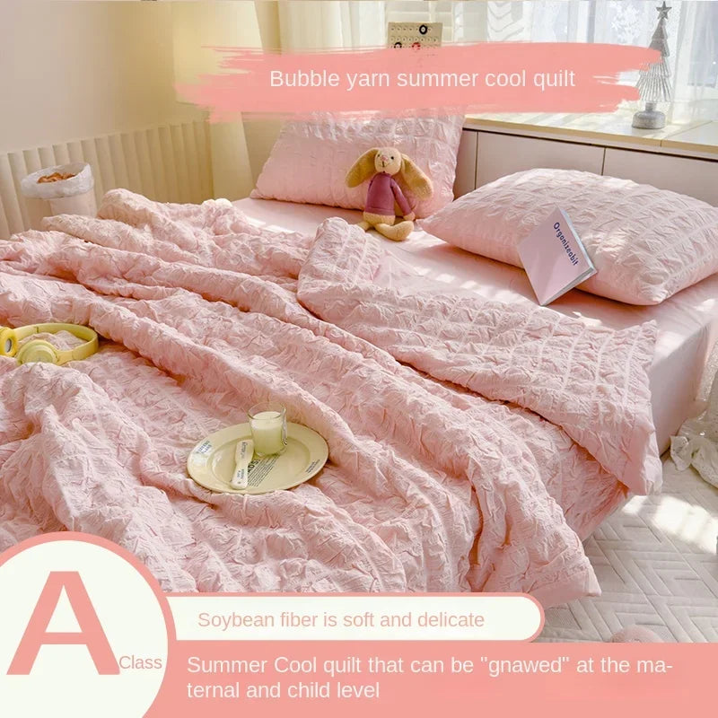Pink bubble yarn summer cool quilt with a stuffed animal on a bed