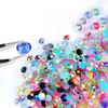 A close-up of various colorful resin and glass rhinestones scattered on a white surface.