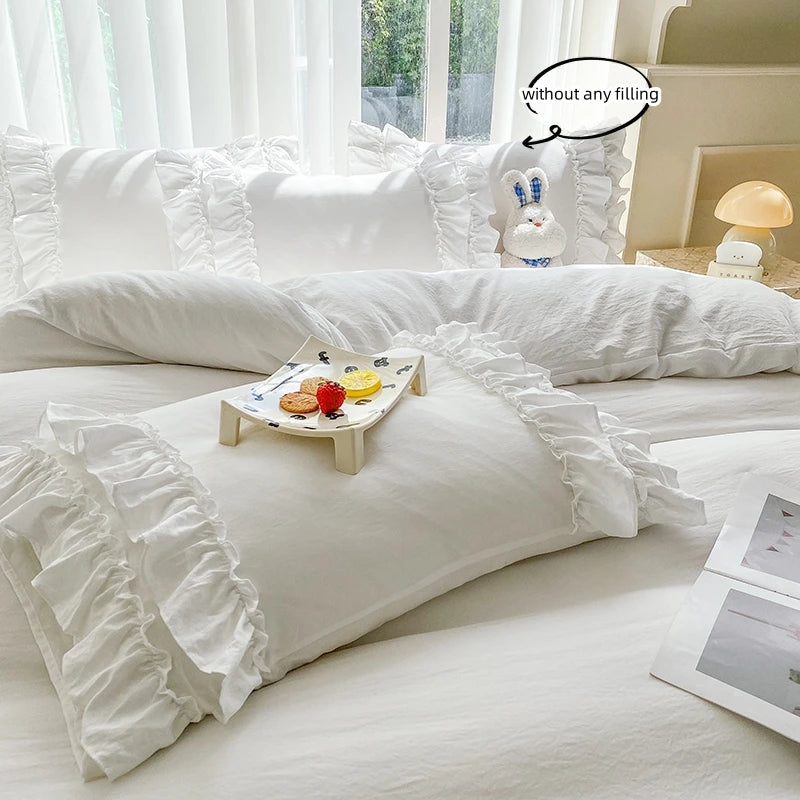 A white ruffled duvet cover set displayed on a bed with natural light and a decorative pillow.