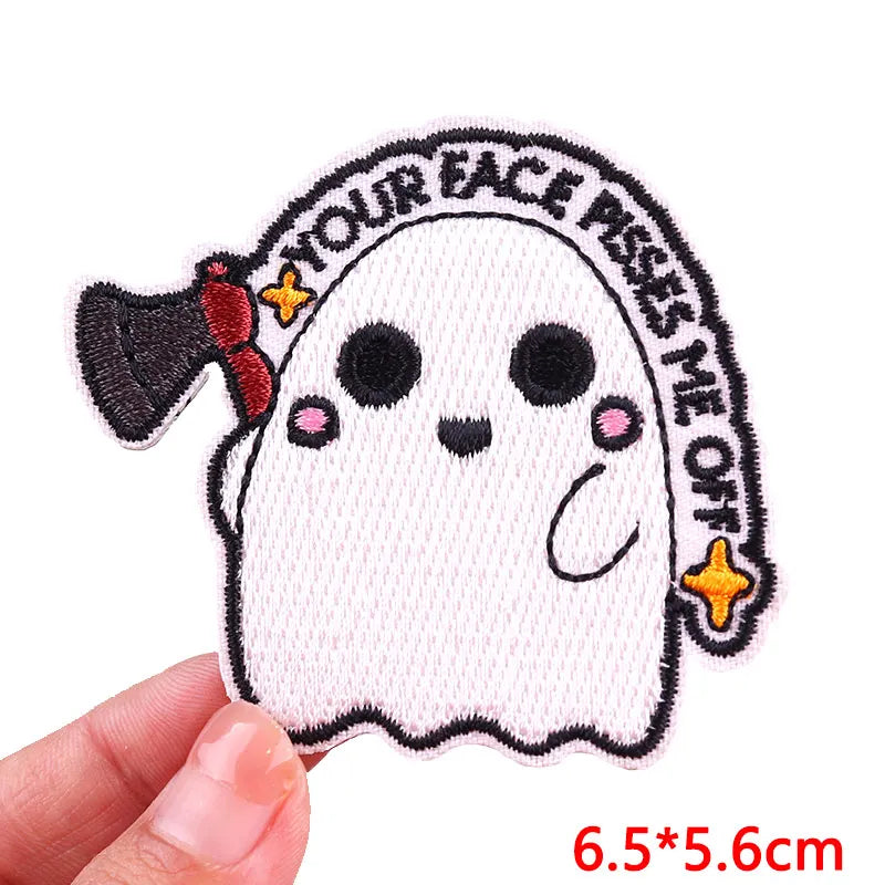 A white ghost-like patch embroidered with black outline and yellow accents on a pink fabric.