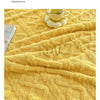 A yellow jacquard taffeta fabric blanket with a quilted texture is shown on a surface, emphasizing gentle care and temperatur