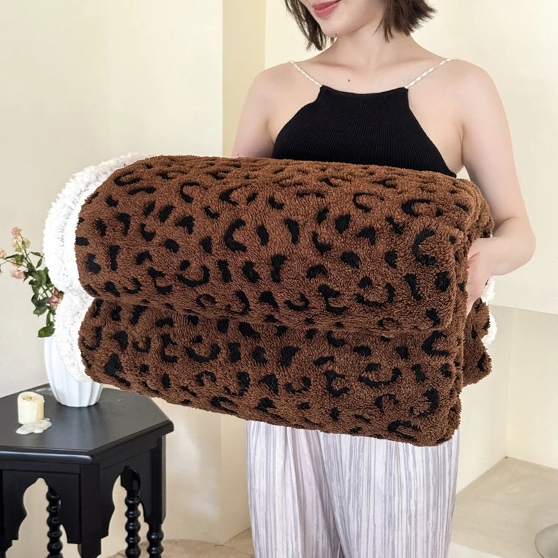 A woman holds a dark brown leopard print knit throw blanket against her chest.