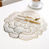 Gold plated peony coasters with gold cutlery placed on a white table.