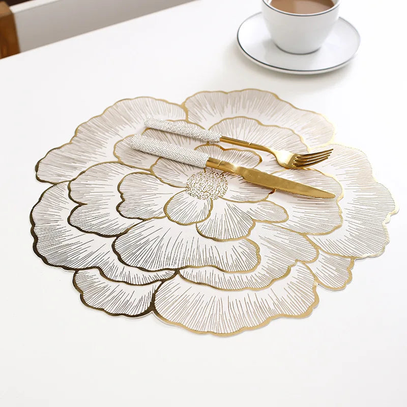 Gold plated peony coasters with gold cutlery placed on a white table.