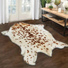 A cream and brown faux animal skin rug with a leopard print pattern placed on a dark wood floor.