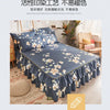 A navy blue bed skirt with a white floral print is displayed on a bed, featuring ruffled edges.