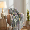 A gray and purple glow-in-the-dark coral fleece blanket draped over a chair in a bright room.