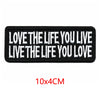Black iron-on embroidered letter patch with white text that reads Love the life you live live the life you love