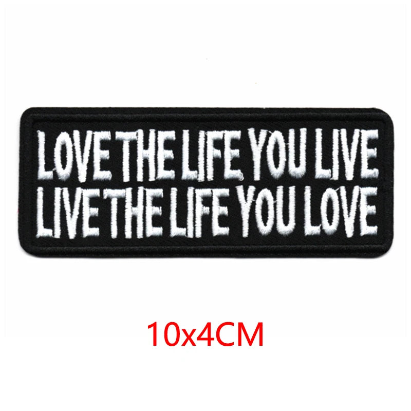 Black iron-on embroidered letter patch with white text that reads Love the life you live live the life you love
