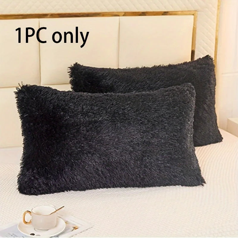 A black faux fur pillow cover is displayed on a white bed, with another matching pillow visible.
