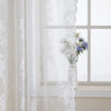 White floral lace sheer curtain hanging in a window with white flowers