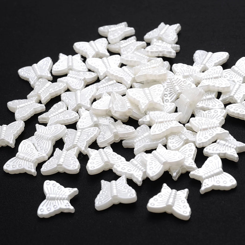 A pile of small, white imitation pearl flower spacer beads for DIY jewelry.