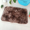 A rectangular, fluffy brown faux fur rug is displayed on a white surface next to a blue sign.