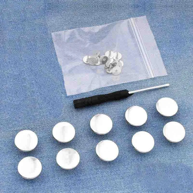A clear plastic bag contains several silver metal button pins on a blue denim fabric background.
