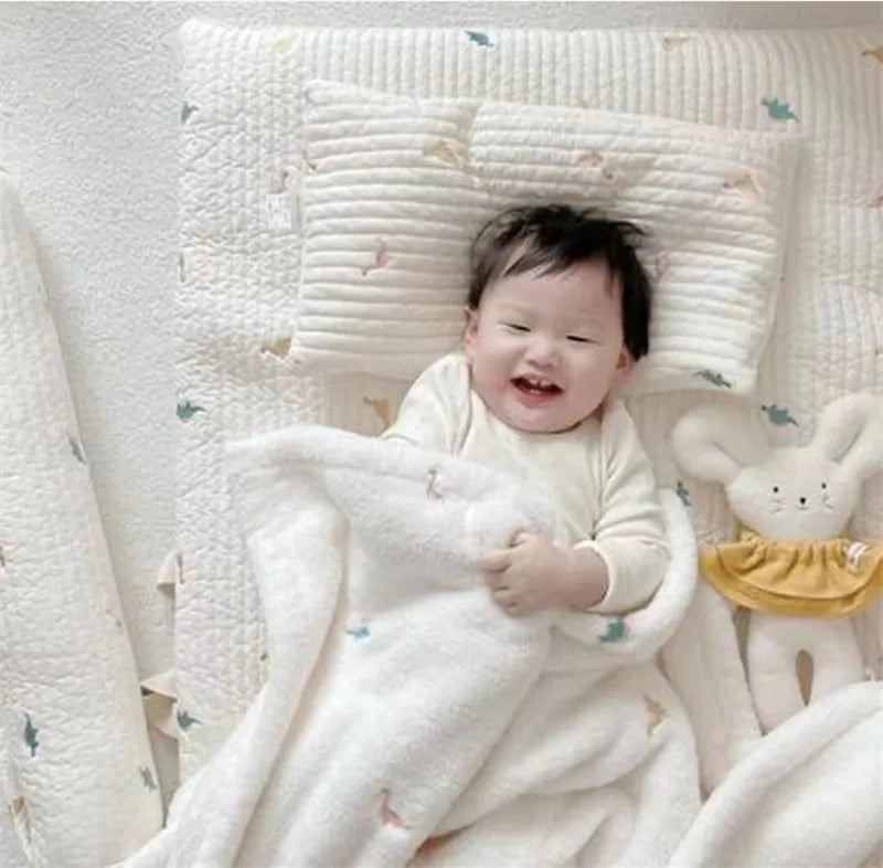 A baby is wrapped in a soft white coral fleece flannel blanket with a light pattern.