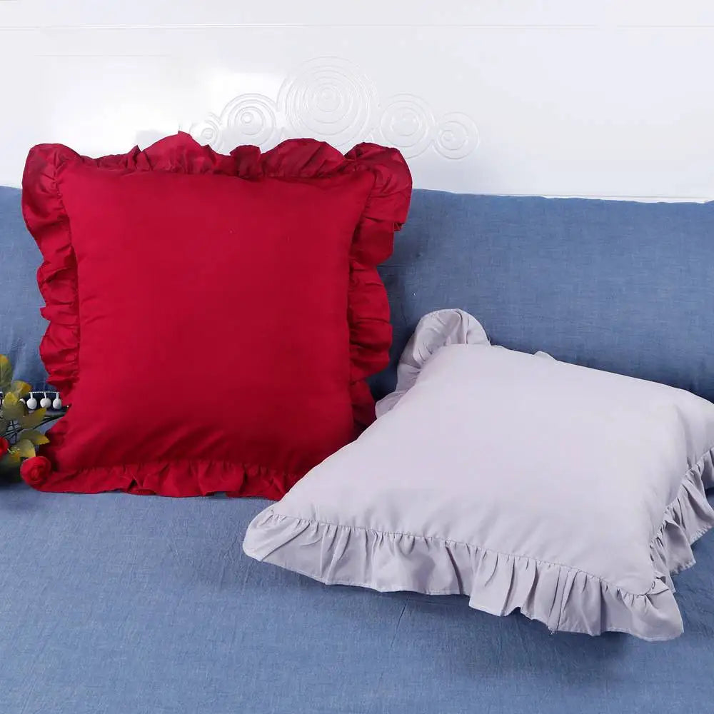 A set of farmhouse ruffled pillow covers in red and white are displayed on a blue fabric surface.
