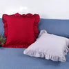 A set of farmhouse ruffled pillow covers in red and white are displayed on a blue fabric surface.
