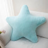 A light blue star-shaped plush throw pillow resting on a white sofa.