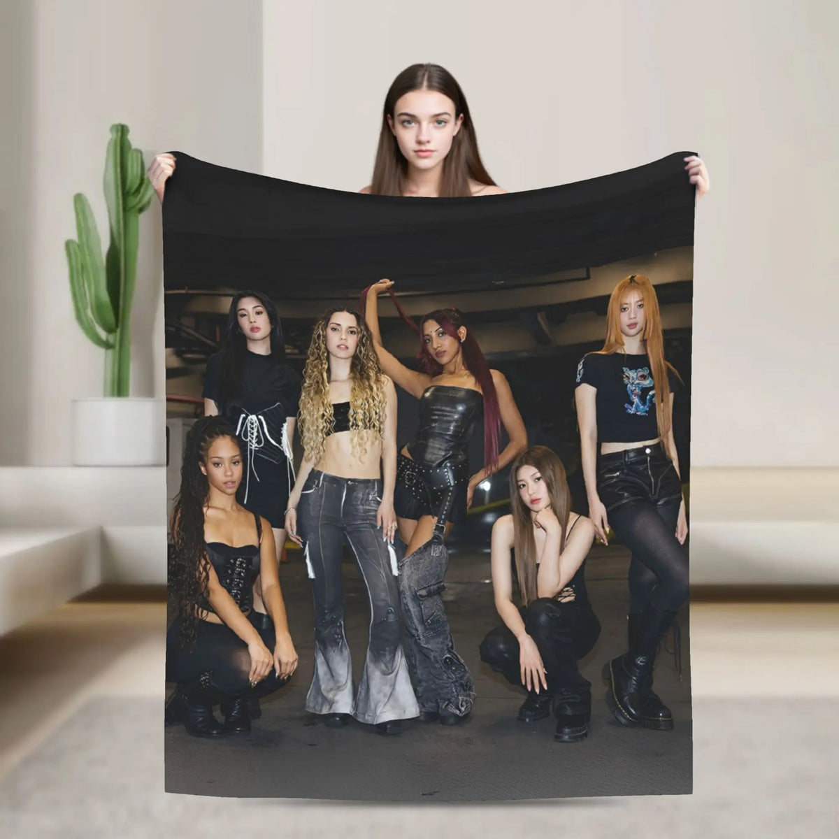 A photo of five women posing with a black fleece throw blanket in a studio setting.