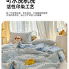 A light blue and white cartoon patterned quilt is displayed on a bed, featuring small animal designs.