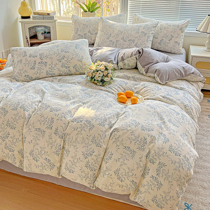 A floral printed bedding set featuring light blue and white patterns on a bed with white window blinds.