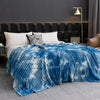 A bright blue and white tie-dye flannel fleece throw blanket draped over a bed.