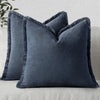 A dark blue linen fringe throw pillow cover resting on a light-colored sofa.