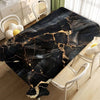 Black marble pattern table cloth draped over a wooden table with white chairs in a bright room.